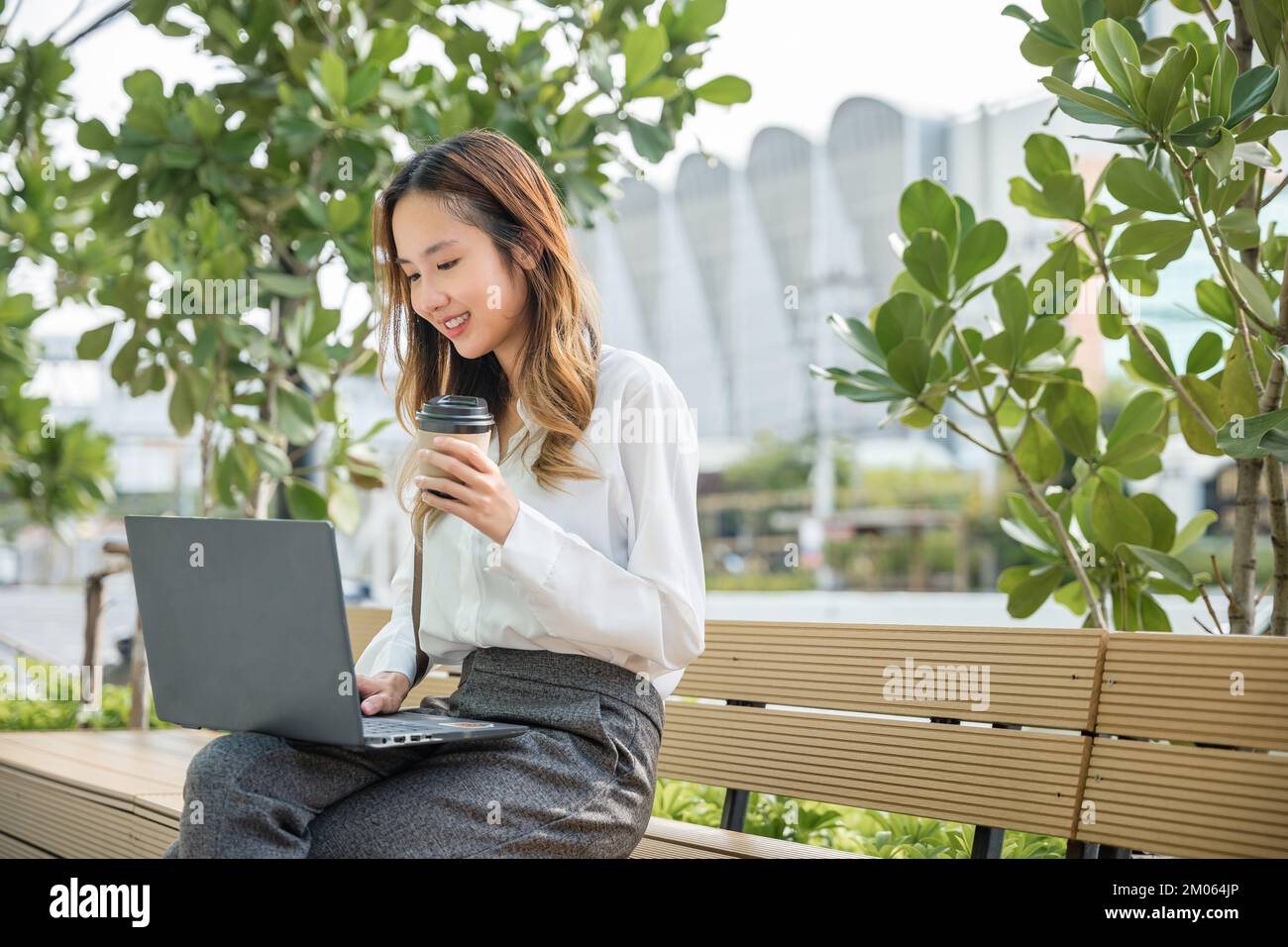 Geschäftsfrau, die mit einem Laptop arbeitet, Außenansicht eines Firmengebäudes Stockfoto