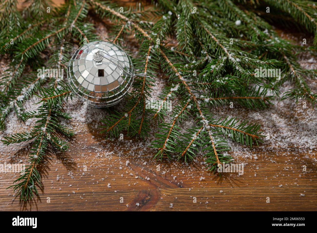 Weihnachtlicher Holzhintergrund mit grüner Fichte, schneebem Dekor, Discokugel Stockfoto