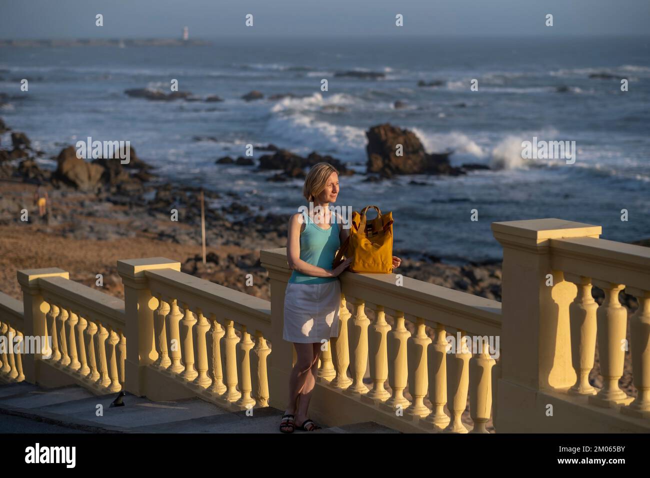Eine Frau mit Rucksack steht auf der Atlantikpromenade in Porto, Portugal. Stockfoto