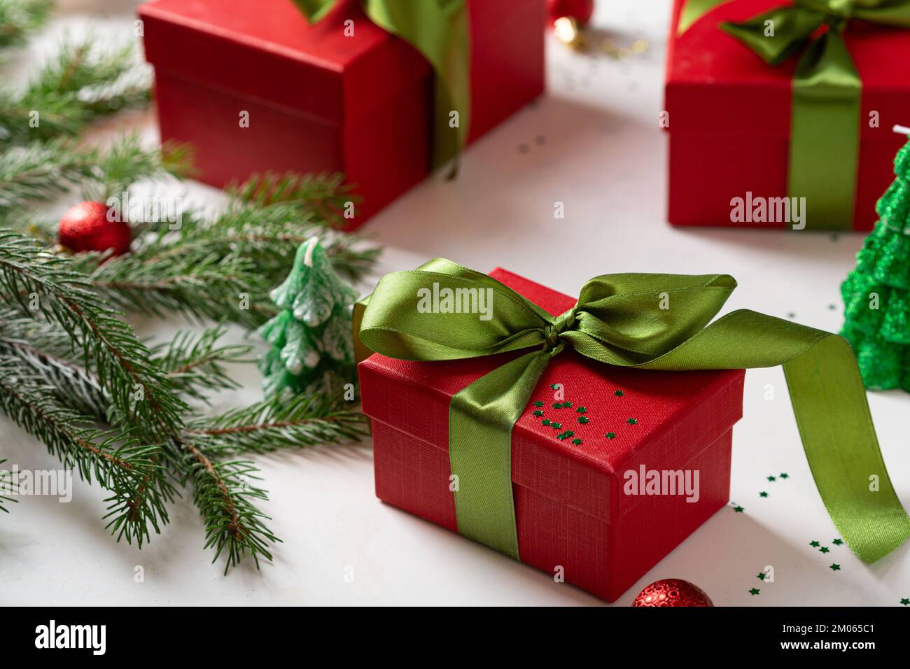 Nahaufnahme der roten Geschenkbox mit grünen Schleifen- und Tannenzweigen Stockfoto