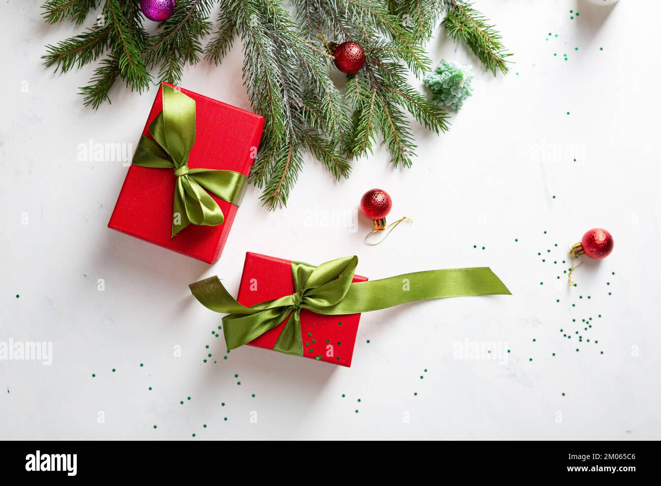 Rote Weihnachtsbox mit grüner Schleife und Tannenzweigen, Draufsicht Stockfoto