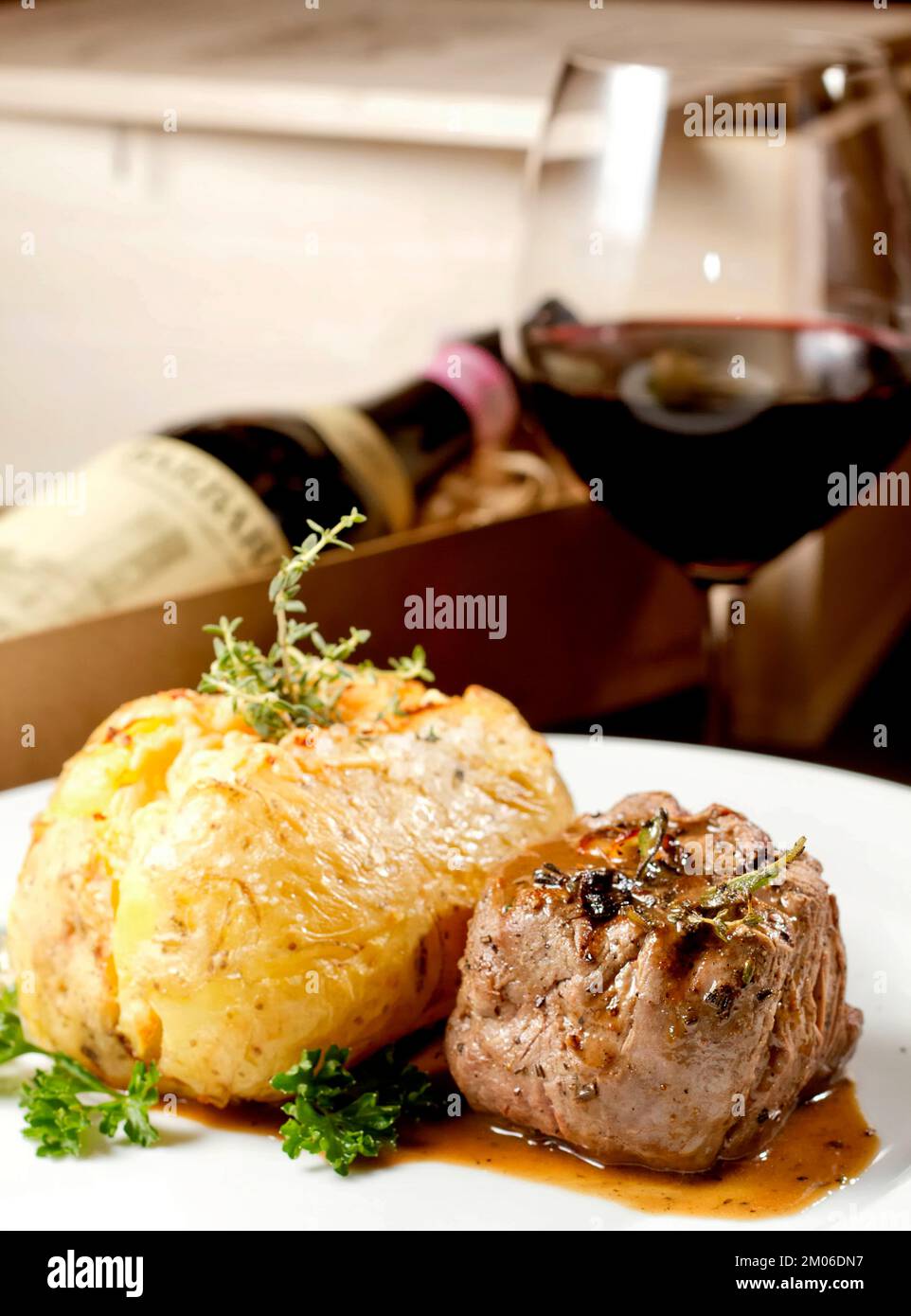 Filet Mignon Rindersteak mit Soße und gefüllter Kartoffel, serviert auf einem Teller, kombiniert mit Rotweinglas und Flasche. Erstklassiges Restaurant Gourmet-Essen Stockfoto