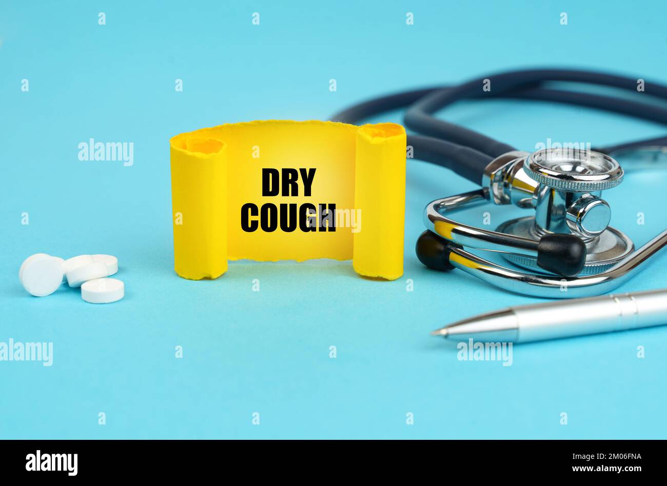 Medizinisches Konzept. Auf einer blauen Oberfläche, einem Stethoskop, Pillen, einem Stift und einem gelben Schild mit der Aufschrift - trockener Husten Stockfoto