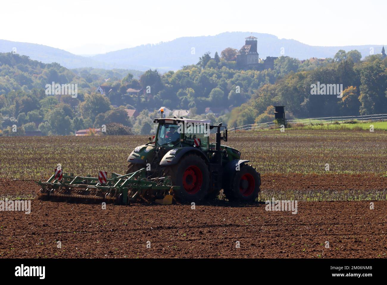 Landwirt eggt das Feld, im Hintergrund Burg Trendelburg, Hessen, Deutschland Stockfoto