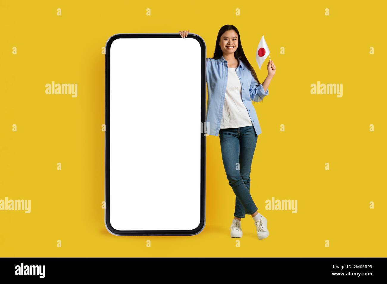 Die fröhliche asiatische Studentenflagge der Jahrtausendwende zeigt Japan mit einem riesigen Smartphone mit leerem Bildschirm Stockfoto