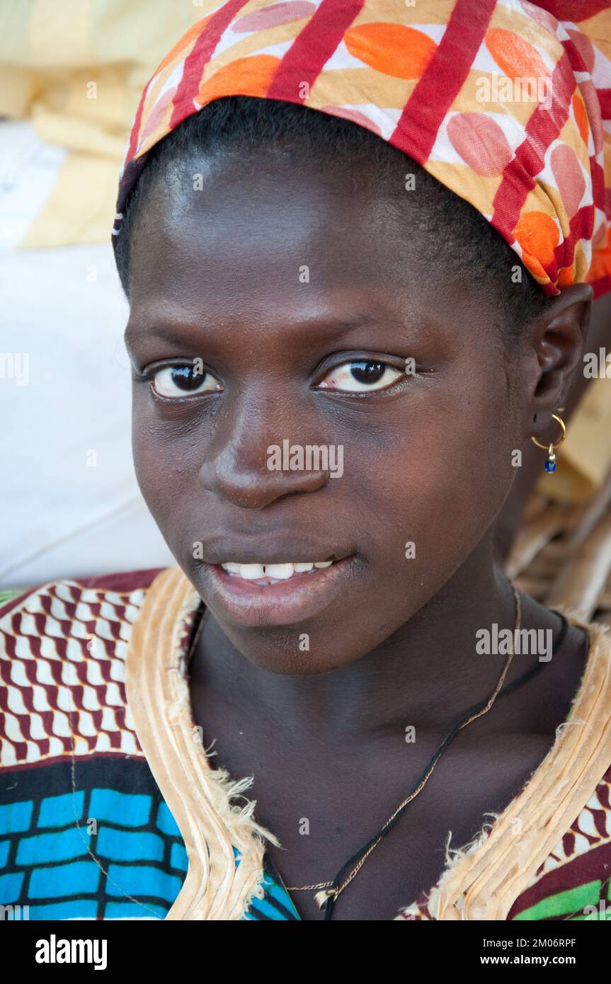Gesichter Afrikas, Afrikaner, Bafata, Guinea-Bissau; schüchterner Ausdruck; Schönes Kopfkleid, Goldkette, goldene Ohrringe Stockfoto