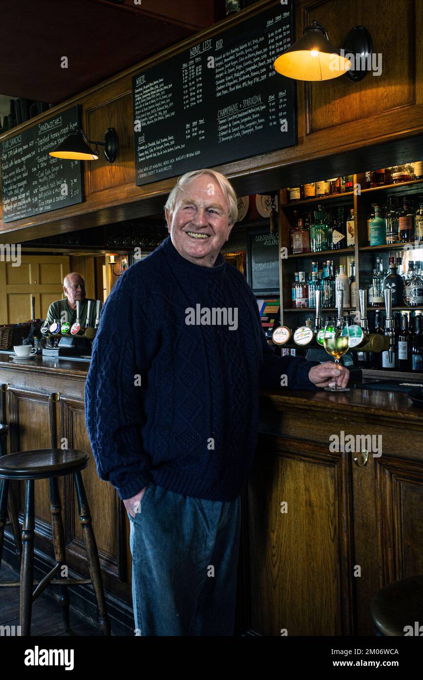 Ein glücklicher Mann stand an der Bar und trank ein Glas Wein. Das Gunton Arms, North Norfolk, England Stockfoto