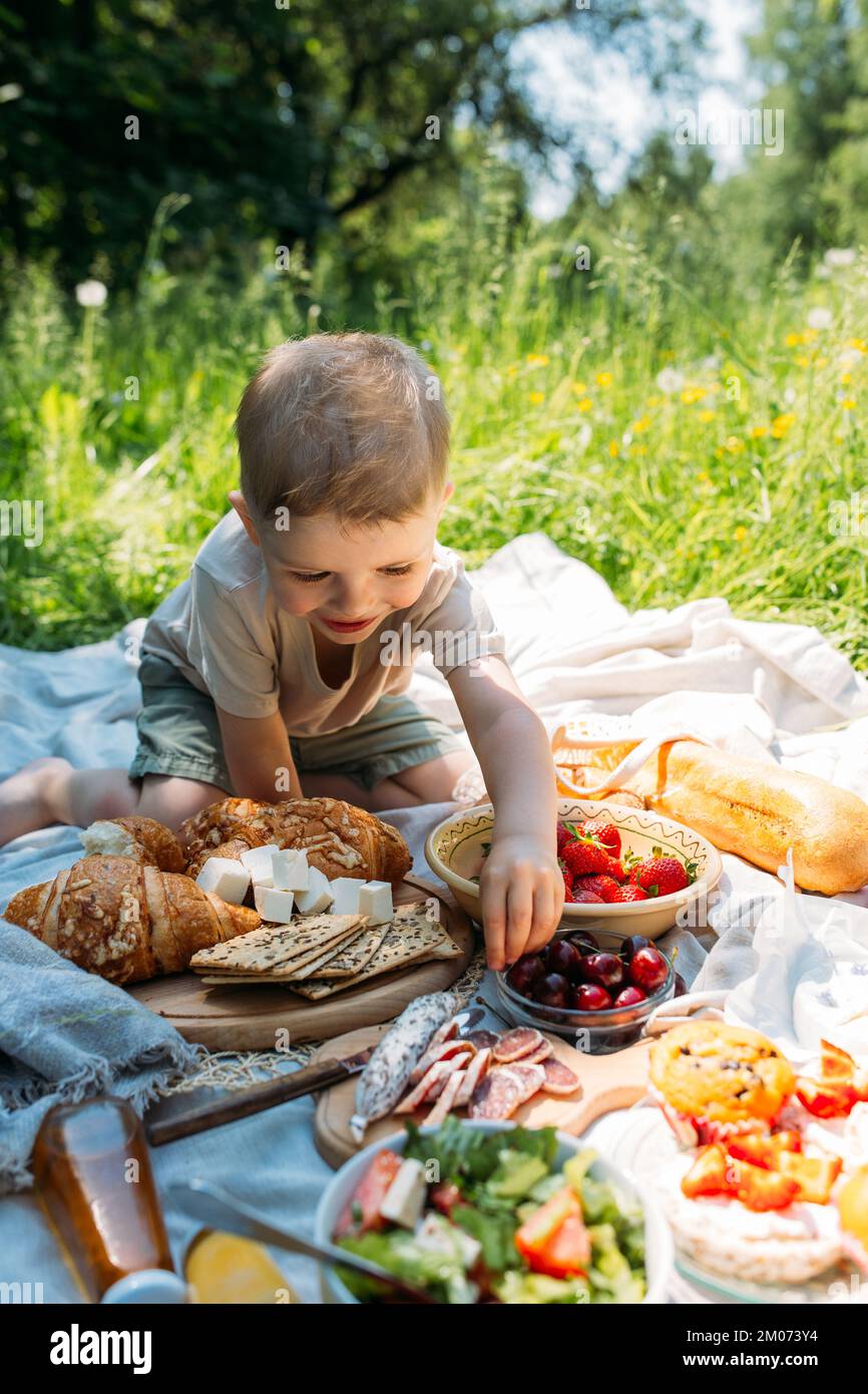 Junge Kind Vorschulkinder auf einem Picknick. Lächelt, Kirschen isst und den Sommer genießt. Stockfoto