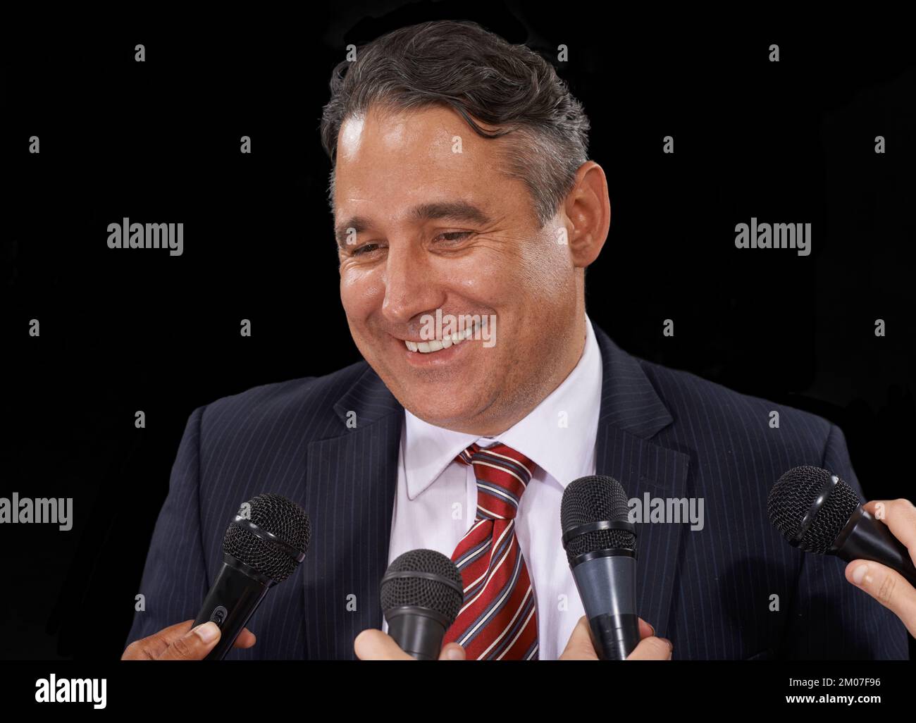 Den Schein aufpeppen. Ein reifer Mann im Anzug, der eine Pressekonferenz auf schwarzem Hintergrund macht. Stockfoto