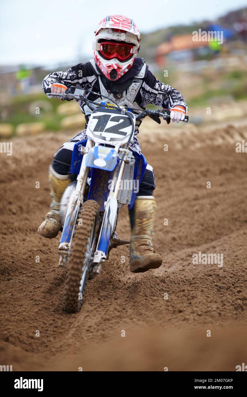 Dominiere die Rennstrecke. Ein junger Motocross-Fahrer, der auf die Kamera zufliegt. Stockfoto