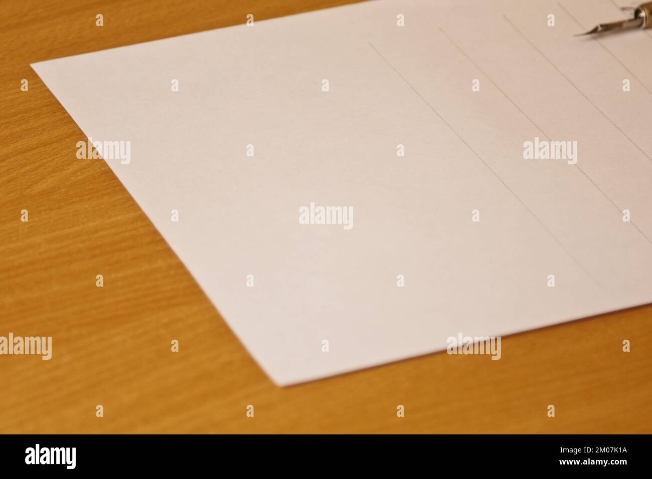 Leeres weißes Blatt mit Streifen. Schreibwaren auf Holzschreibtisch aus nächster Nähe. Rechtschreibunterricht und Caligraphie-Übungen. Vorlage, Layout, Stockfoto