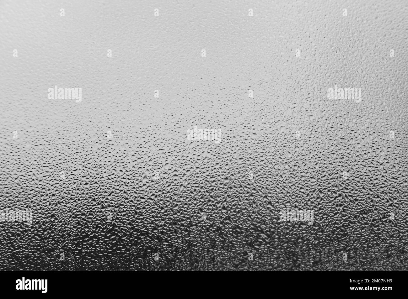 Tautropfen und Kondensation auf Glas, kalte Jahreszeit und hohe Luftfeuchtigkeit an Fenstern in Häusern, Kondensationsstruktur mit Wassertropfen. Stockfoto