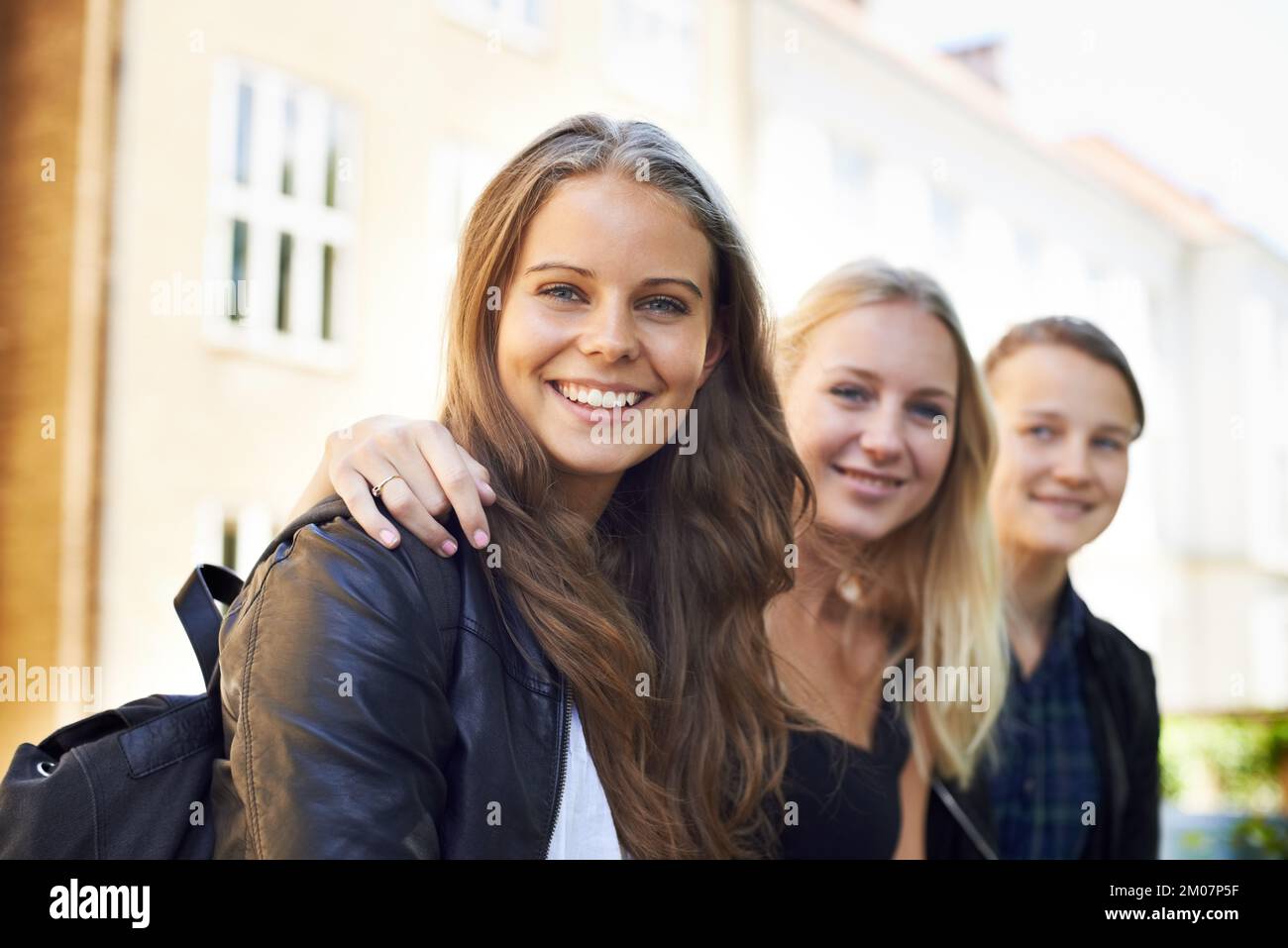 Spaß mit Freunden haben. Drei Freunde im Teenageralter, die nebeneinander sitzen und lächeln. Stockfoto