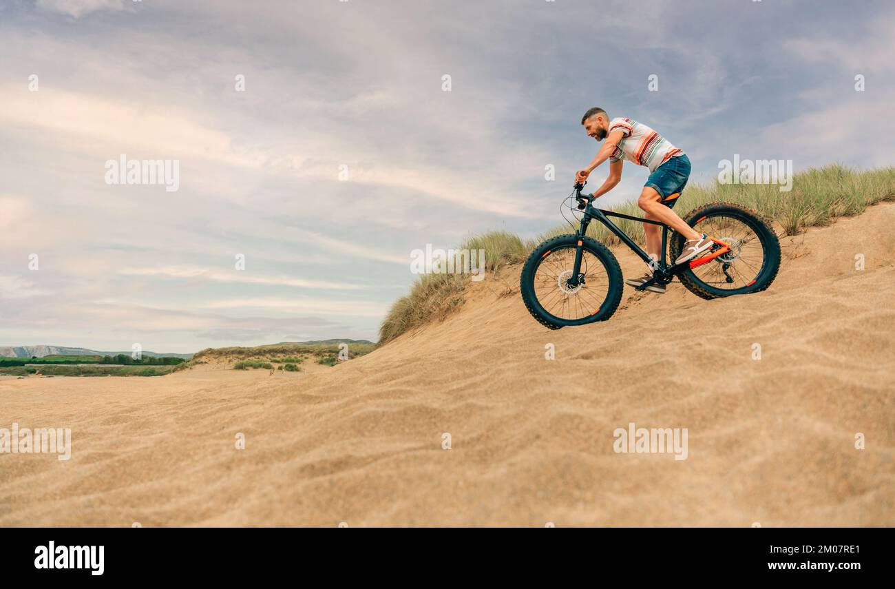 Mann, der mit einem fetten Fahrrad durch die Stranddünen fährt Stockfoto