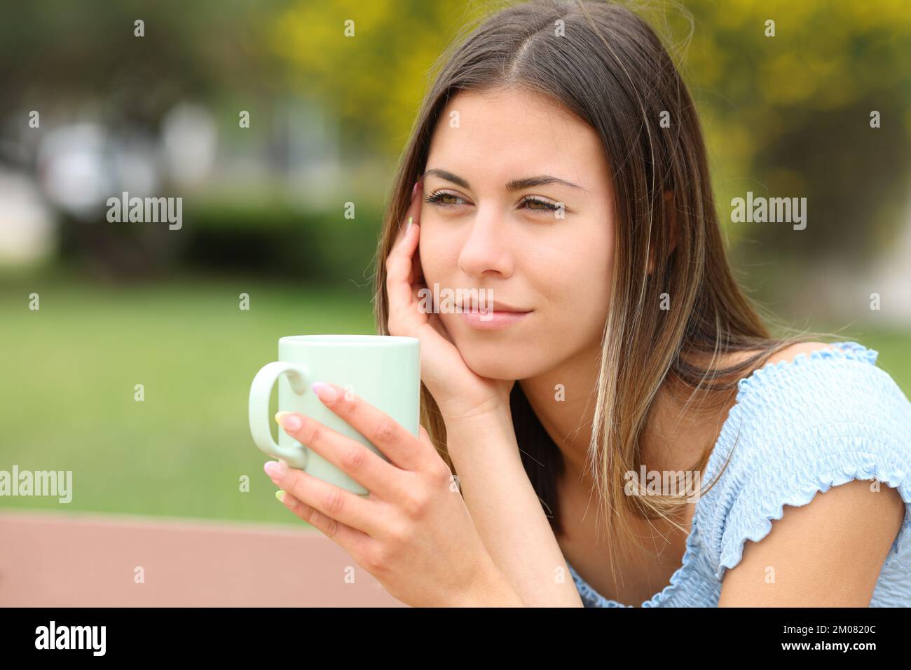 Glücklicher Teenager, der sich entspannt beim Kaffeetrinken in einem Park entspannen kann Stockfoto