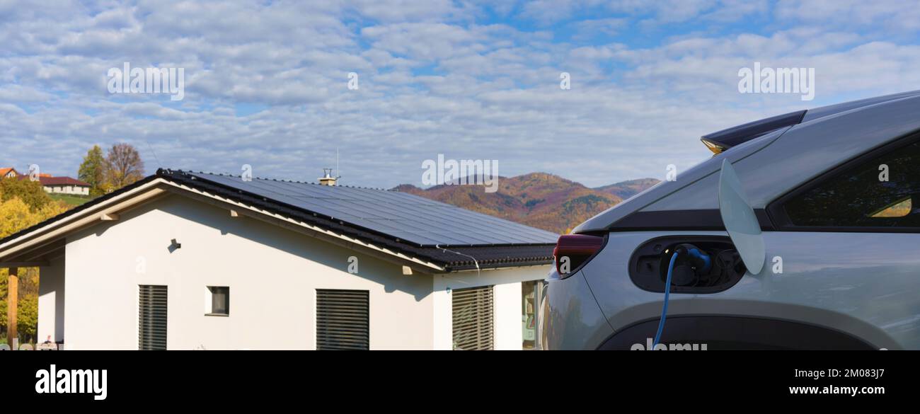 Laden eines Elektroautos zu Hause, nachhaltiges Transportkonzept. Stockfoto