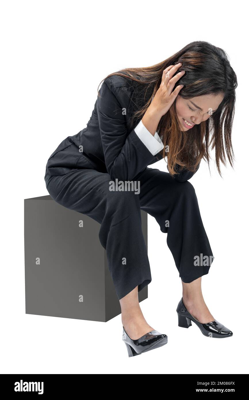 Asiatische Geschäftsfrau, die mit frustriertem Ausdruck auf weißem Hintergrund sitzt Stockfoto