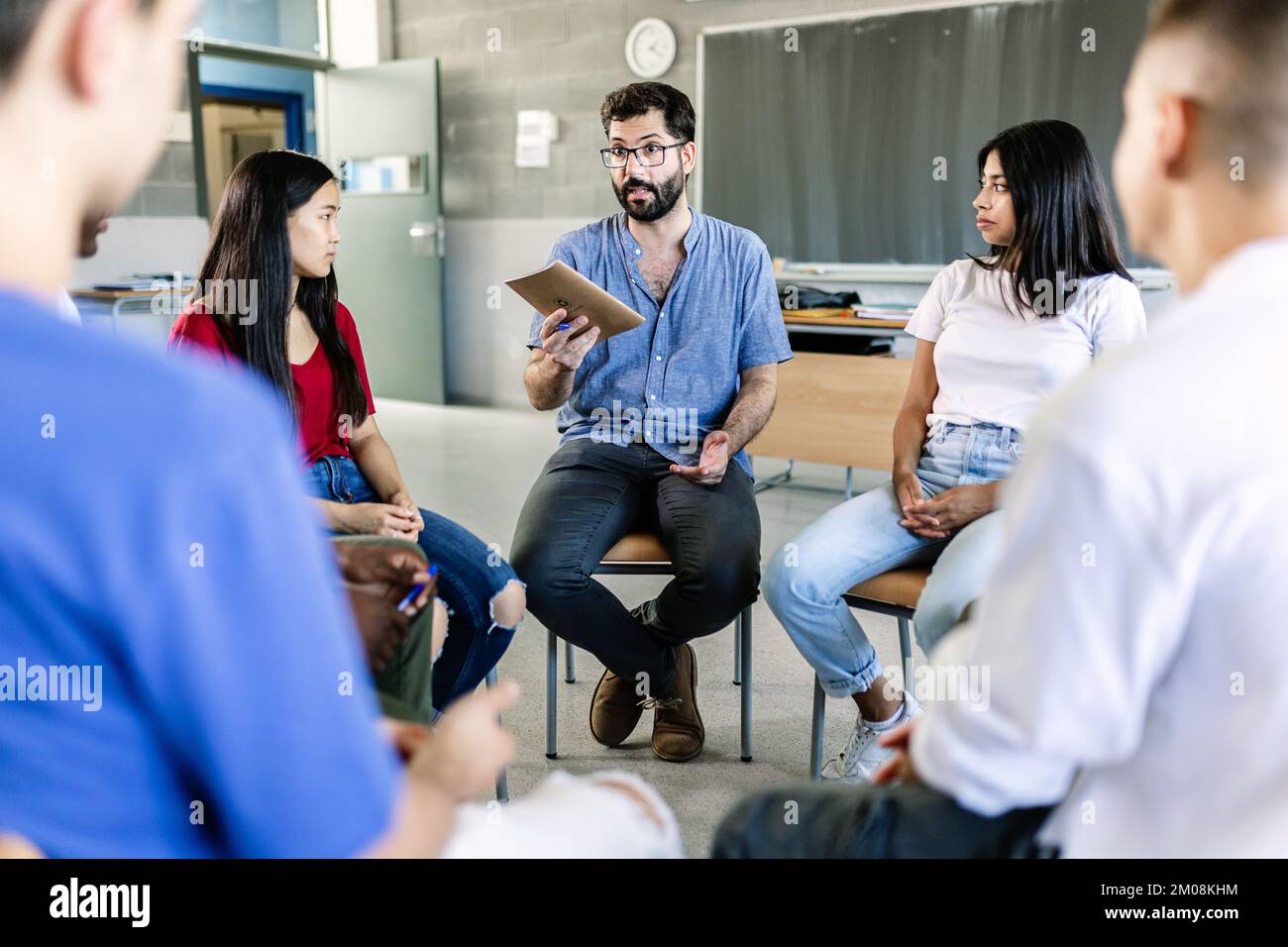 Verschiedene Oberschüler, die während der Diskussionsgruppe mit dem Lehrer sprechen Stockfoto