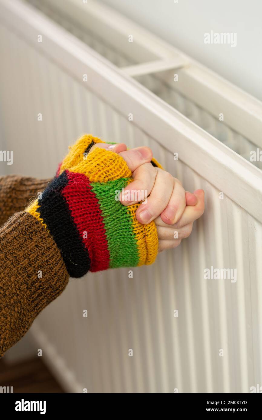 Nahaufnahme von Händen in fingerlosen Handschuhen, die sich gegen einen Gaskühler aufwärmen Stockfoto