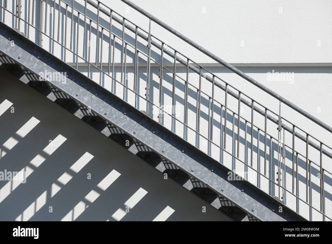 Außentreppe aus Stahl mit Schatten an einer weißen Hauswand, Deutschland, Europa Stockfoto