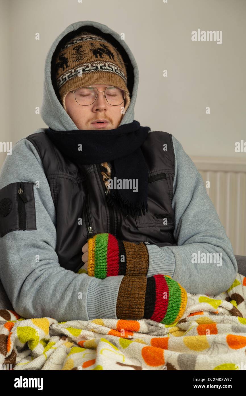 Ein junger Mann, der Winterkleidung in einem Haus trägt Stockfoto