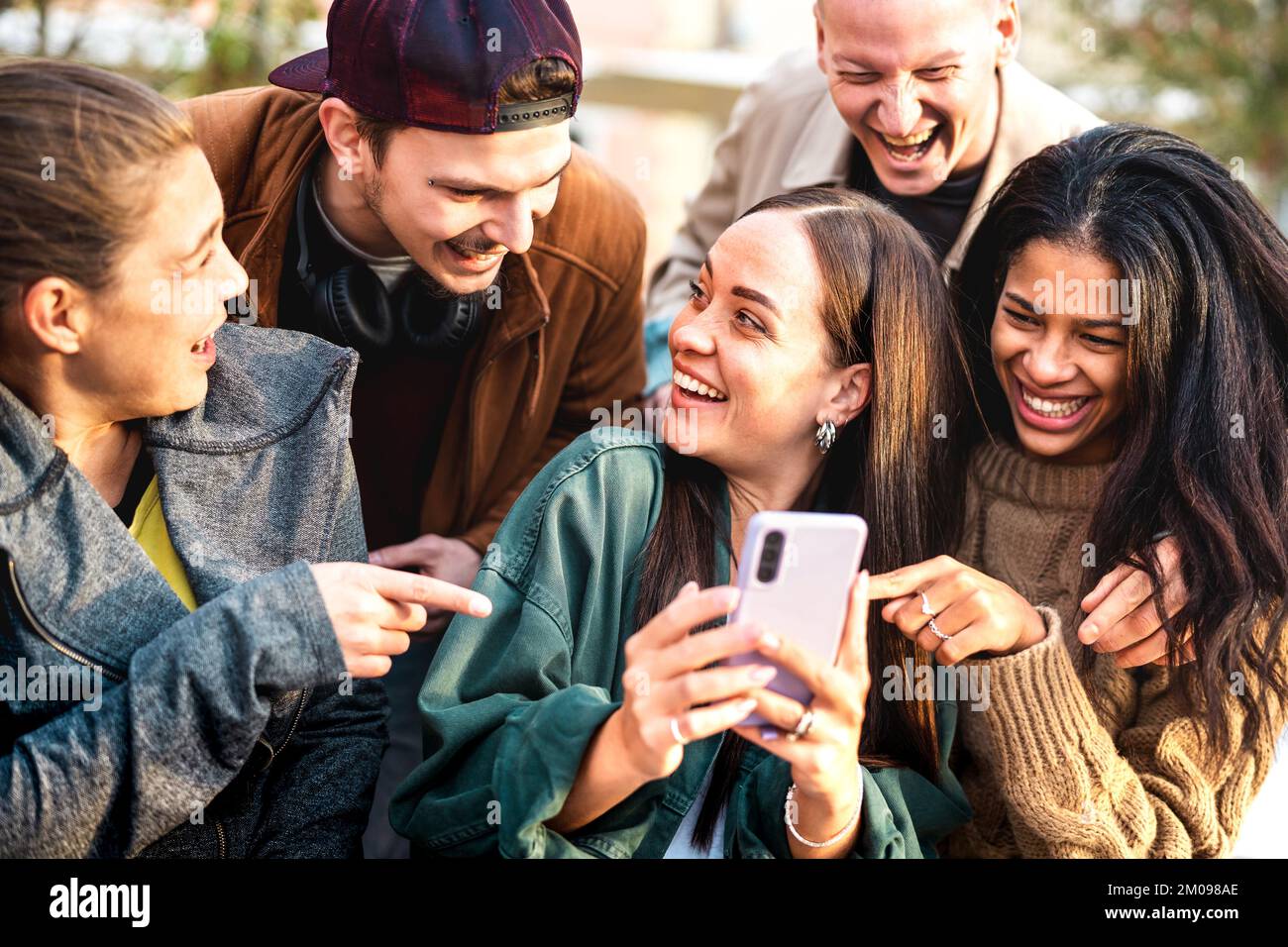 Multikulturelle junge Menschen, die im städtischen Hof Spaß mit ihrem Mobiltelefon haben – Happy boys and girls verbringt Zeit miteinander, um lustige Inhalte online zu teilen Stockfoto