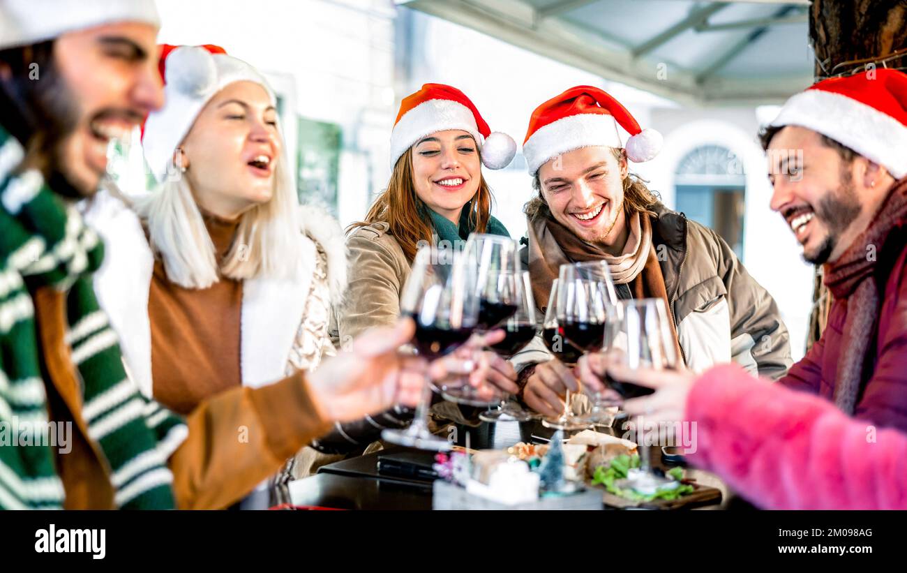 Trendige junge Leute auf dem weihnachtsmann feiern Weihnachten mit Rotwein auf dem Food Street Market - Winterfreundschaftskonzept Stockfoto