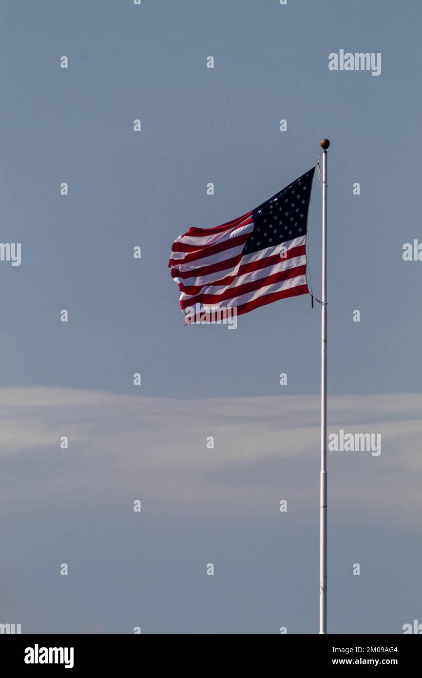 Ein vertikales Bild der Flagge der USA, die in der Luft schwankte und an einen weißen Stab geklebt war Stockfoto