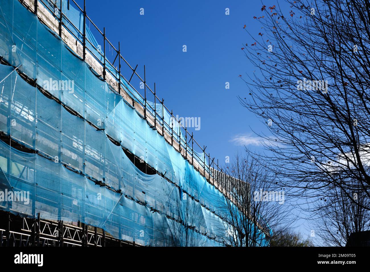 Gerüste und Netze, die die Seite eines hohen Gebäudes bedecken Stockfoto