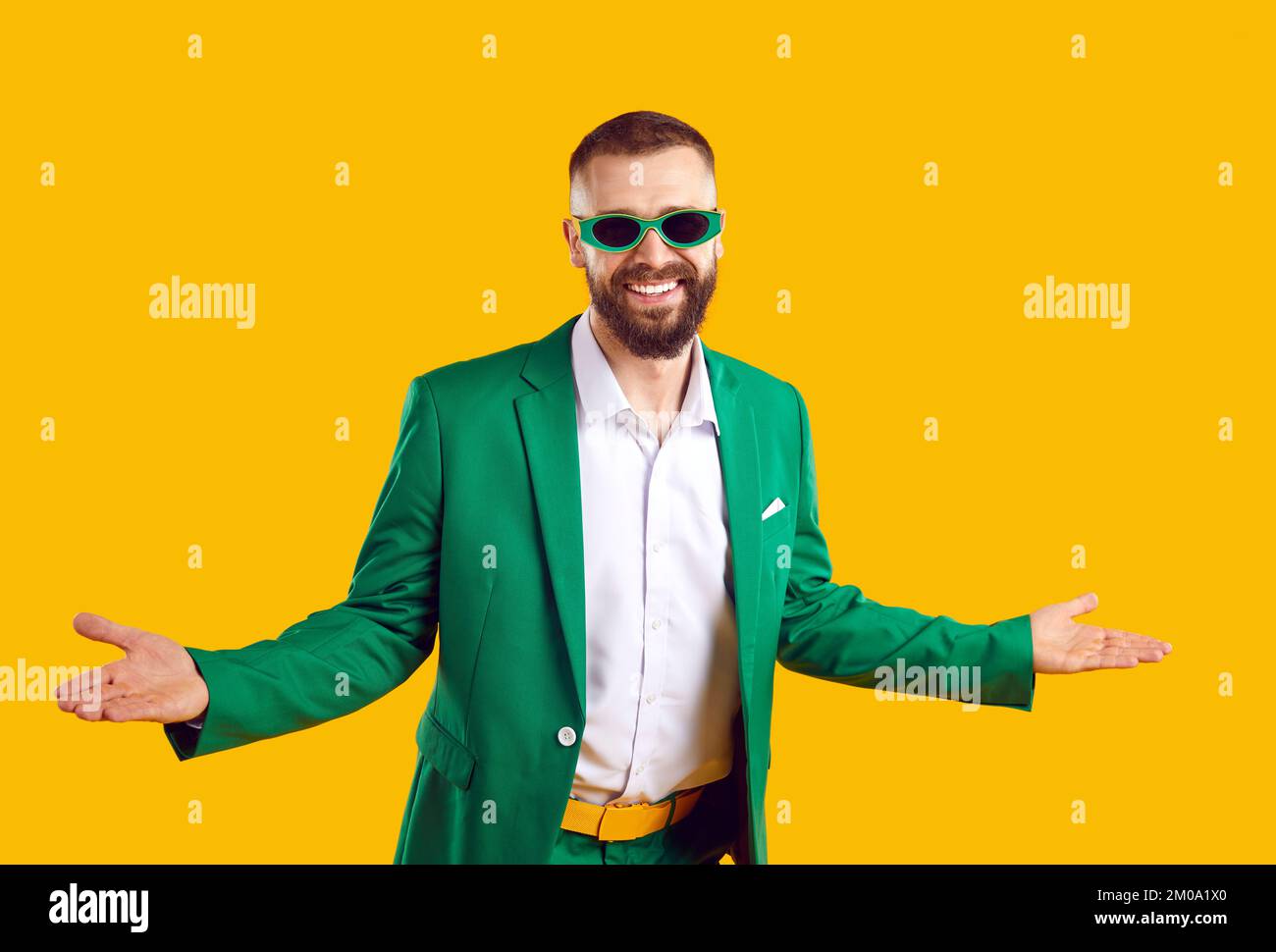 Der lustige Mann in grünem Anzug und Sonnenbrille spreizt die Arme und begrüßt Sie zur St. Patrick's Day Party Stockfoto