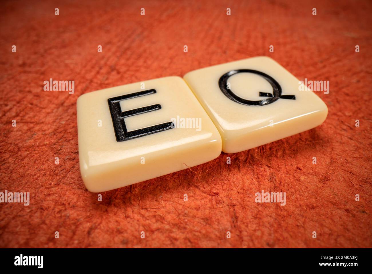 EQ – Symbol für emotionale Verständlichkeit in elfenbeinfarbenen Fliesen auf strukturiertem, Rindenpapier, Makroaufnahme Stockfoto