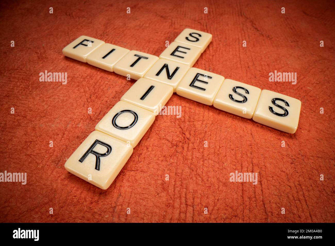 Senior Fitness Kreuzworträtsel mit elfenbeinfarbenen Buchstabensteinen auf texturiertem orangefarbenem Papier, Gesundheits- und Lifestyle-Konzept Stockfoto
