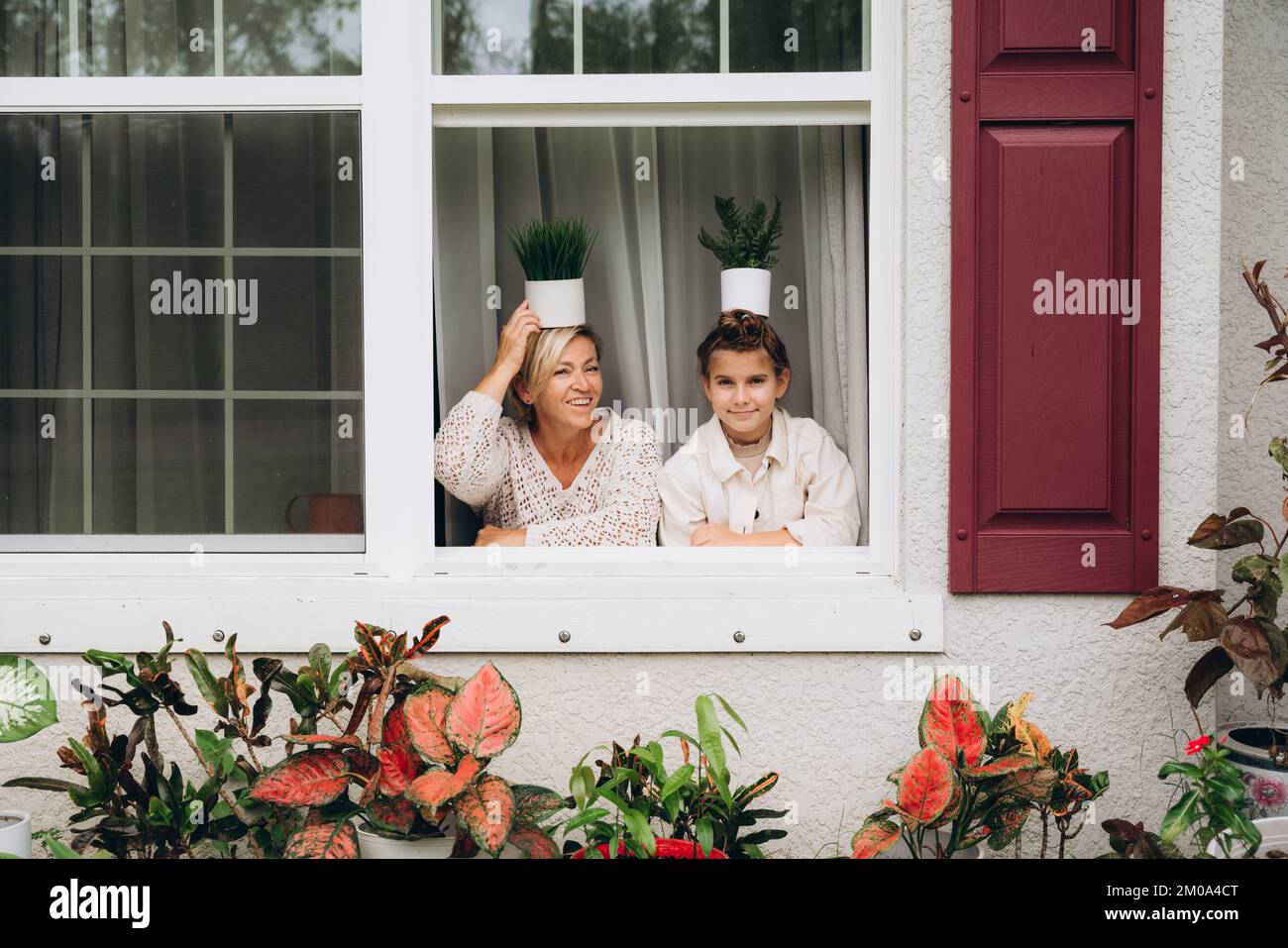 Lächelnde Mutter und Tochter im Fenster mit Blick in den Garten Stockfoto