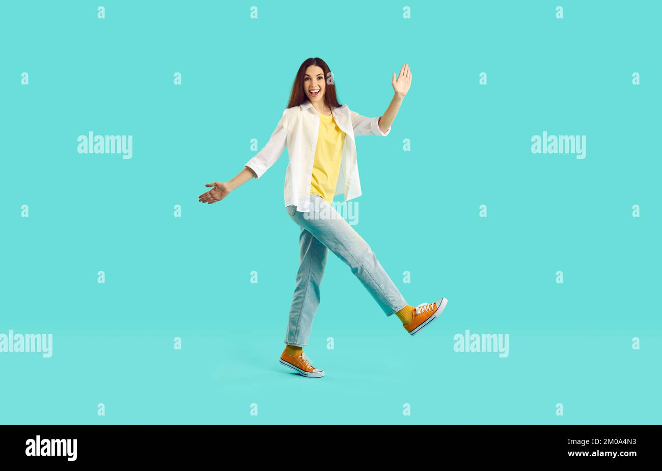 Fröhliche, sorgenfreie junge Frau, die Spaß und lustige Spaziergänge hat, isoliert auf türkisfarbenem Hintergrund. Stockfoto