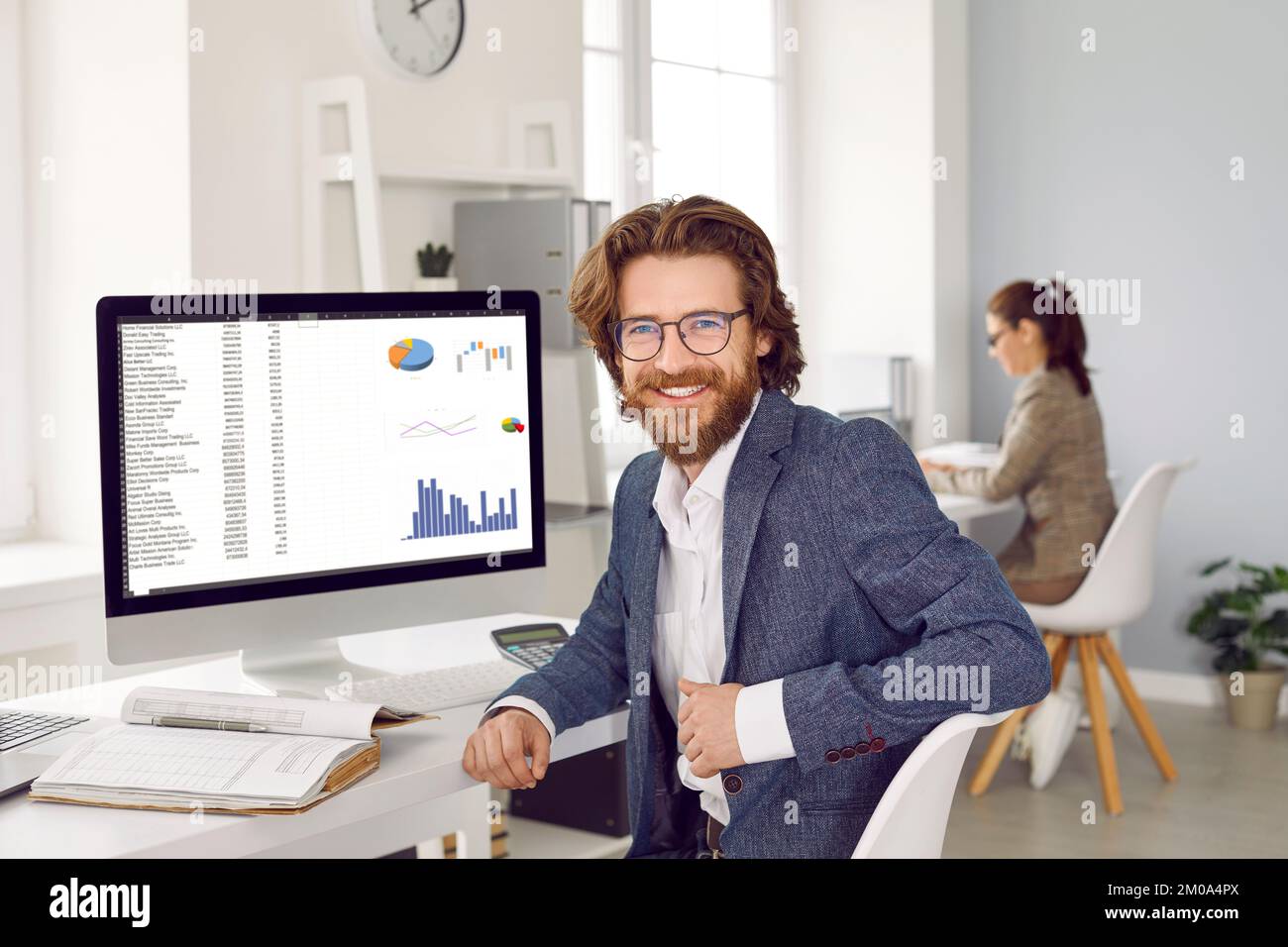 Glücklicher Finanzbuchhalter oder Datenanalytiker, der mit einem Computer am Schreibtisch sitzt Stockfoto