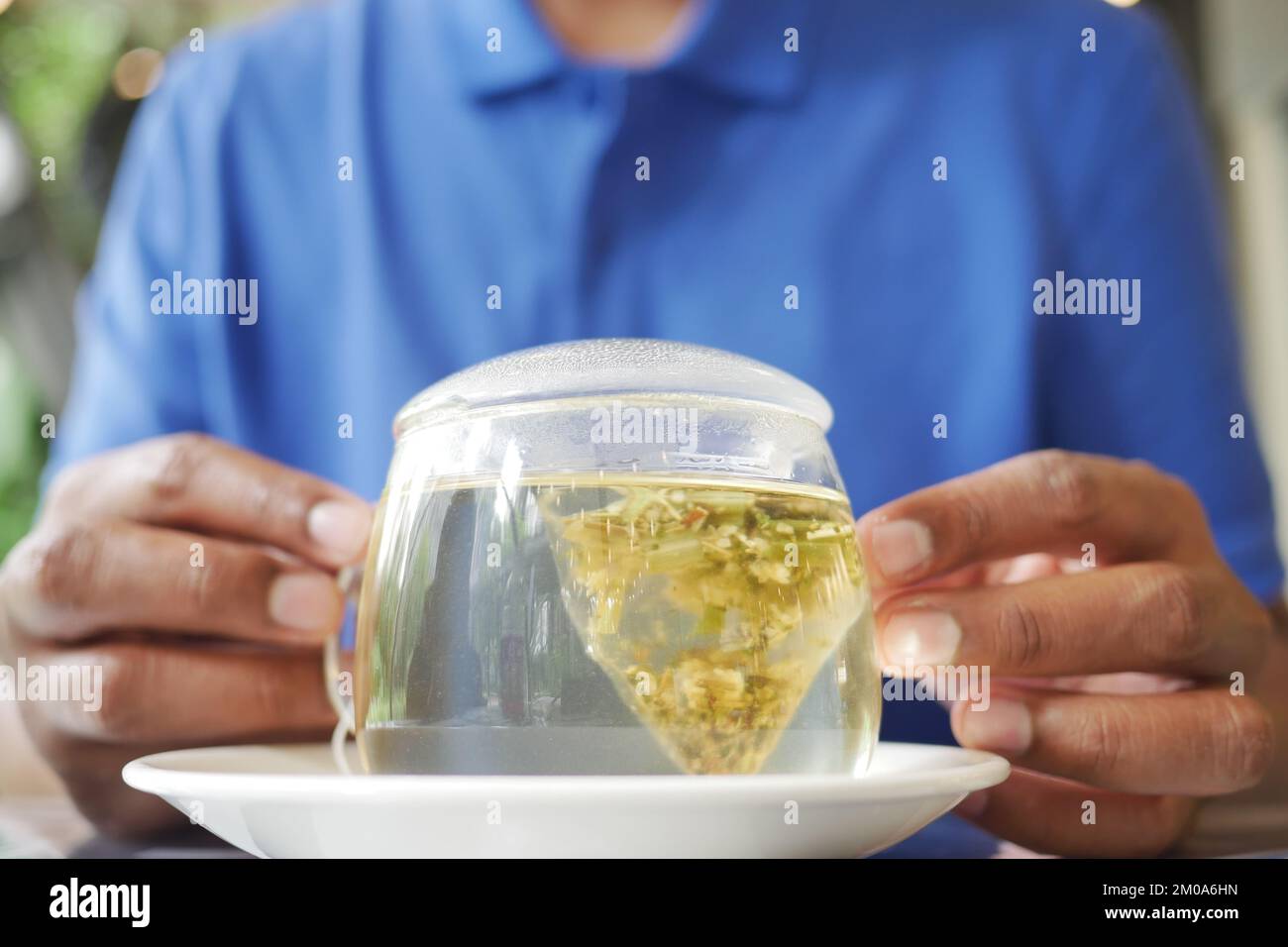 Junge Männer, die eine Tasse grünen Tee und einen Teebeutel auf dem Tisch halten, Stockfoto