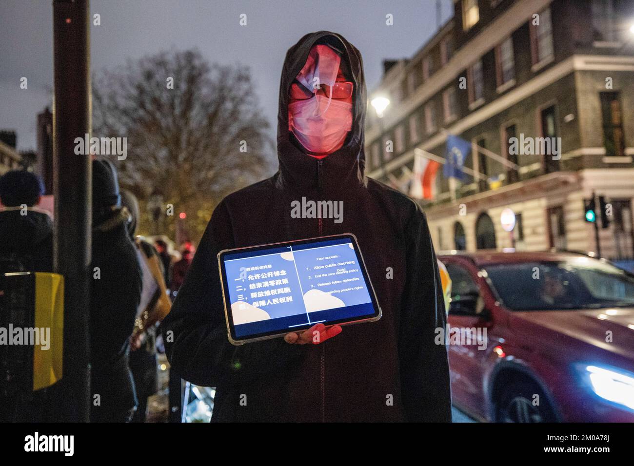 Ein Protestteilnehmer, der mehrere Gesichtsmasken im Gesicht hat und eine Tafel hält, die die Forderungen der Chinesen an ihre Regierung während der Demonstration vor der chinesischen Botschaft in London illustriert. Chinesische Studenten, die derzeit in London studieren, versammelten sich bei der chinesischen Botschaft in London, um gegen die Lockdown-Politik in China zu protestieren. Letzte Woche kam es in China zu einer massiven Welle von Protesten, da 10 Menschen in einem Urumqi in der Nordwestregion Chinas aufgrund der unmenschlichen COVID-Lockdown-Politik getötet wurden. (Foto: Hesther Ng/SOPA Images/Sipa USA) Stockfoto