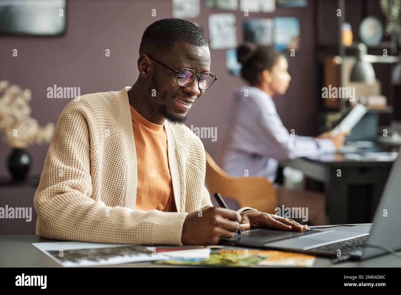Lächelnder Designer, der das Firmenlogo auf einem grafischen Tablet zeichnet Stockfoto