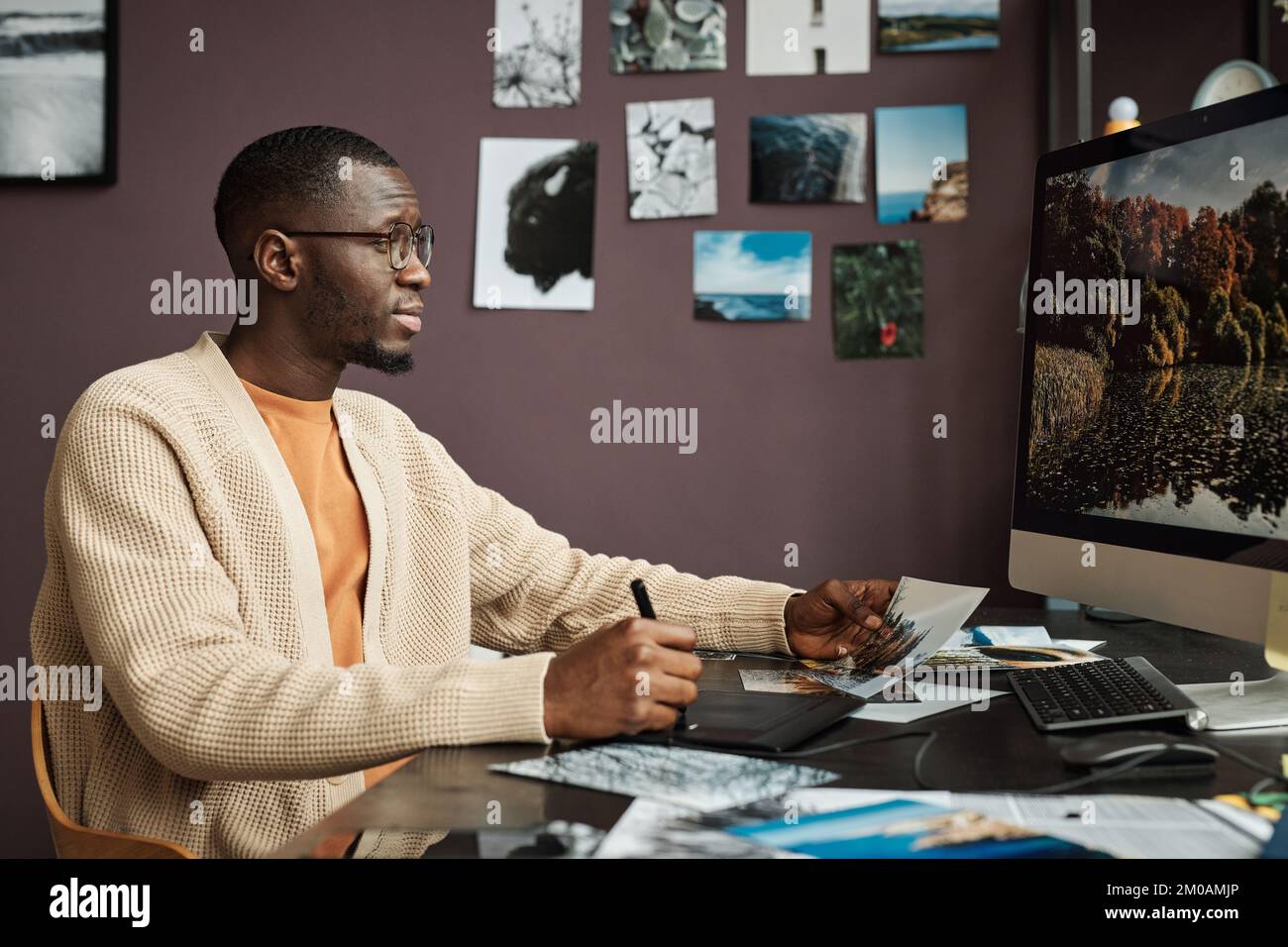 Kreativer Schwarzer bearbeitet Landschaftsfotos am Computer, wenn er von zu Hause aus arbeitet Stockfoto
