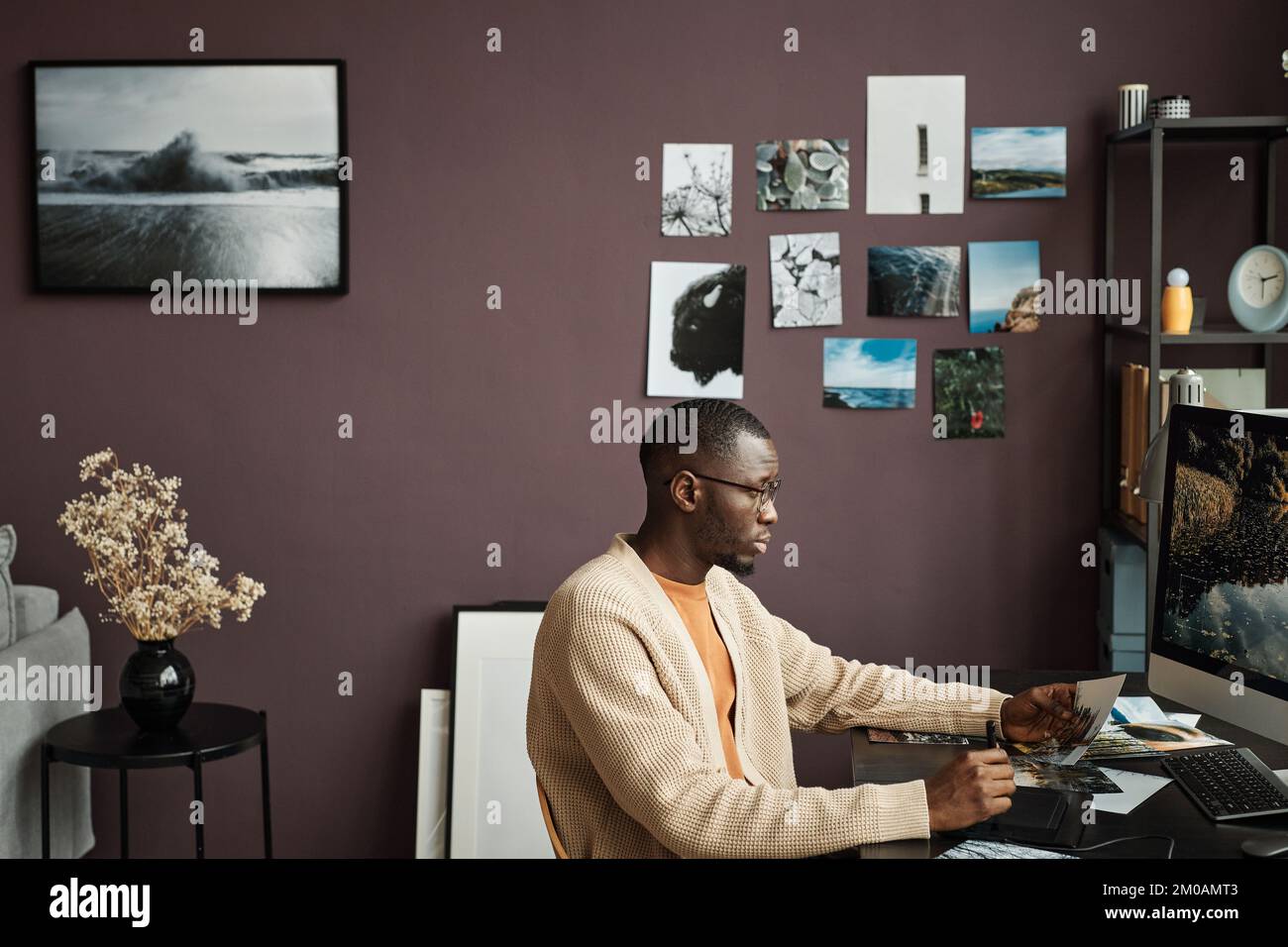 Kreativer Schwarzer retuschiert Landschaftsfotos auf dem Computer in seinem Heimbüro Stockfoto
