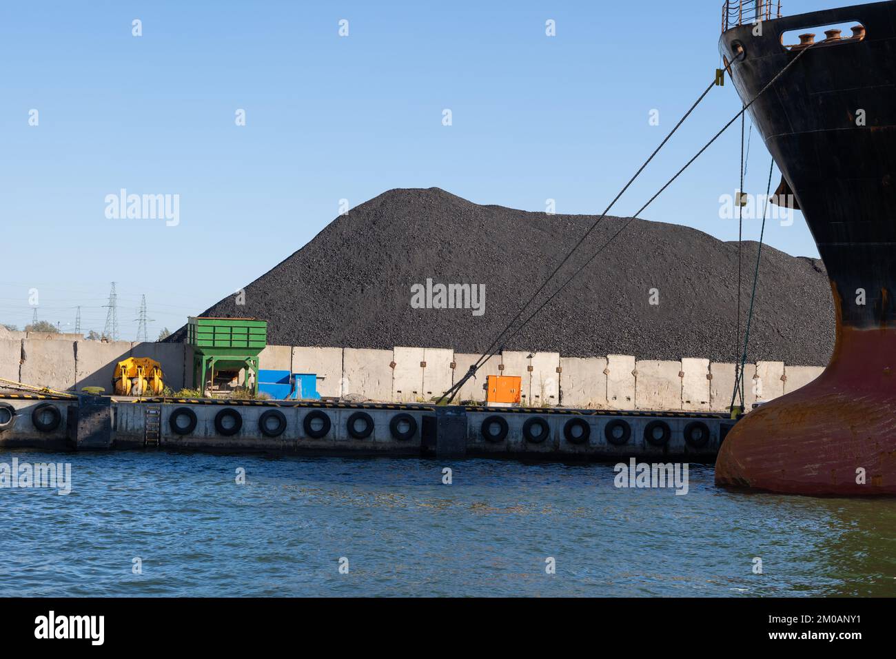 Großer Kohlehaufen und Bug eines Frachtschiffs am Seehafen. Stockfoto