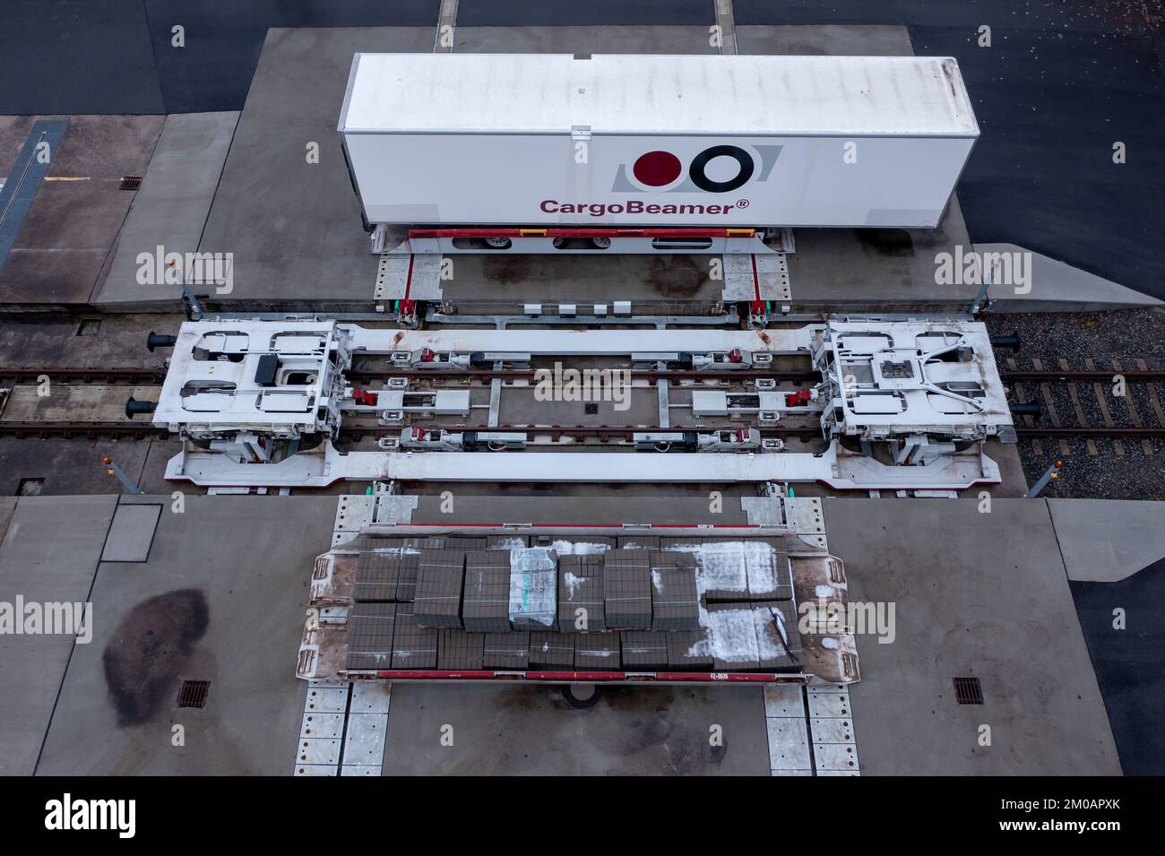 05. Dezember 2022, Sachsen, Leipzig: Ein Auflieger wird an einem Güterbahnhof mit einer neuen Ladetechnik auf einen Eisenbahnwagen verladen. Das Leipziger Unternehmen CargoBeamer möchte den Güterverkehr innerhalb Europas effizienter und umweltfreundlicher gestalten. Im neu entwickelten Terminal können Lkw-Anhänger mit Hilfe einer sogenannten Laderampe seitlich auf den Waggon gefahren werden. Dadurch wird das Problem umgangen, dass fast alle Lkw-Anhänger nicht mit einem Kran angehoben werden können, was die Beladung der Schiene kostspielig und nicht lohnenswert macht. Das erste Terminal des Unternehmens ist in Calais in Nordfrankreich in Betrieb Stockfoto