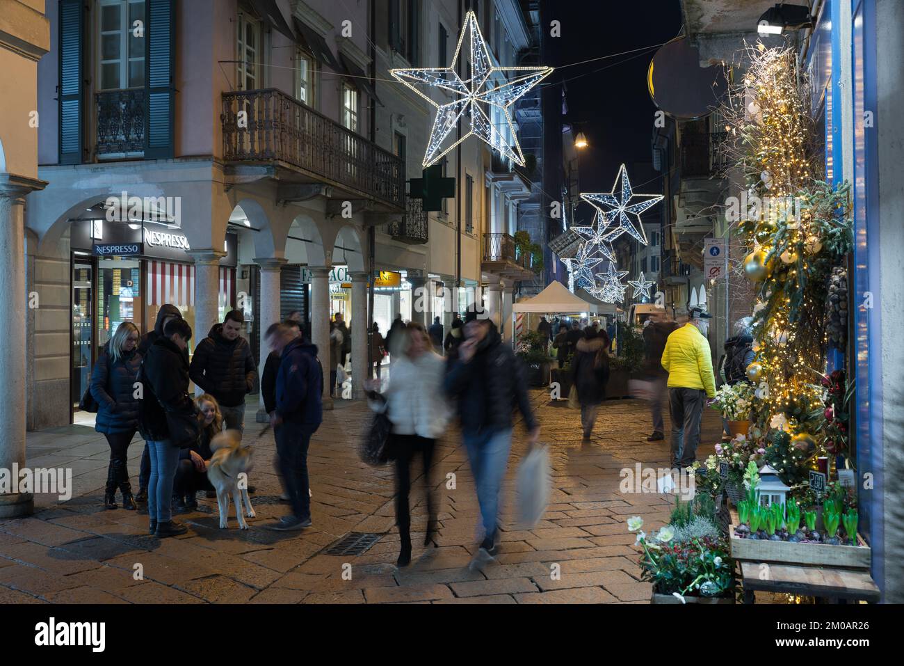Nachtleben in der Stadt während der Weihnachtsfeiertage. Straße mit Menschen, Lichtern und weihnachtsdekorationen. Corso Matteotti in Varese City Stockfoto