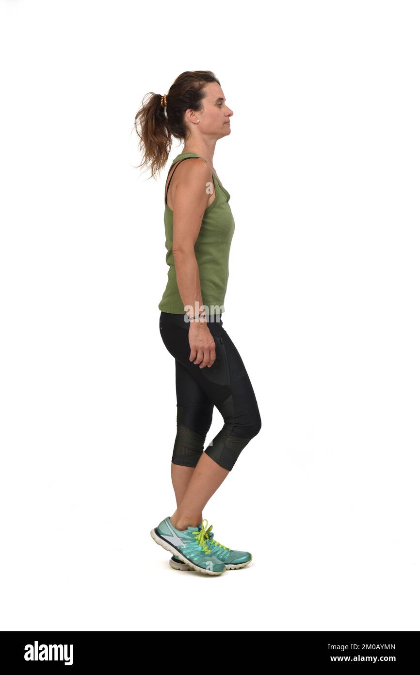 Seitenansicht einer seriösen Frau mit Sportkleidung, die auf weißem Hintergrund läuft, Stockfoto