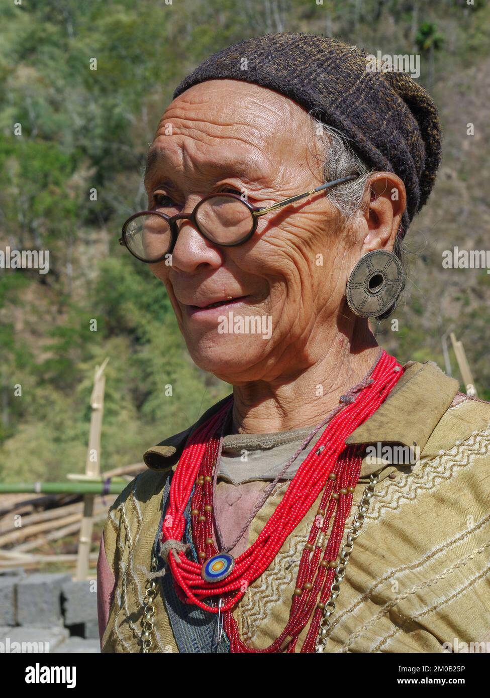 Raga, Arunachal Pradesh, Indien - 11 20 2013 : Porträt einer lächelnden alten Nyishi-Stammesfrau mit Brille in traditionellen Ohrringen und roten Halsketten Stockfoto