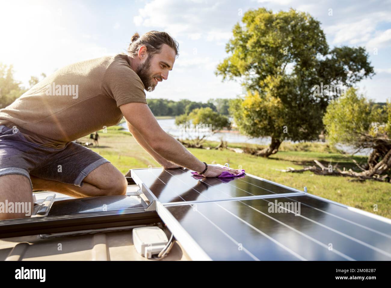 Ein Mann, der die Solarpaneele auf dem Dach eines Wohnwagens reinigt Stockfoto