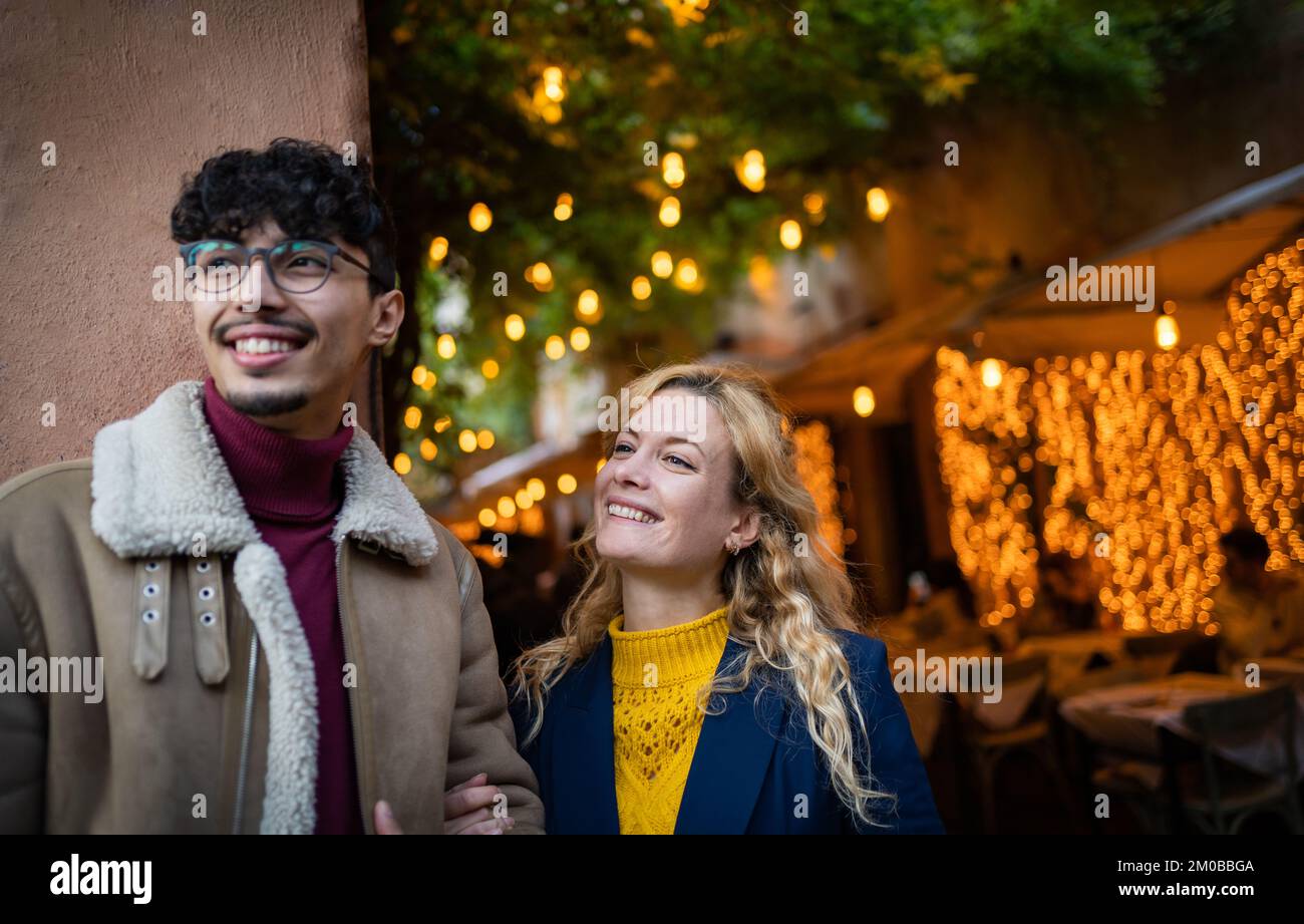 Halblanges Foto eines jungen, multiethnischen Paares, das lächelt und Menschen ansieht Stockfoto