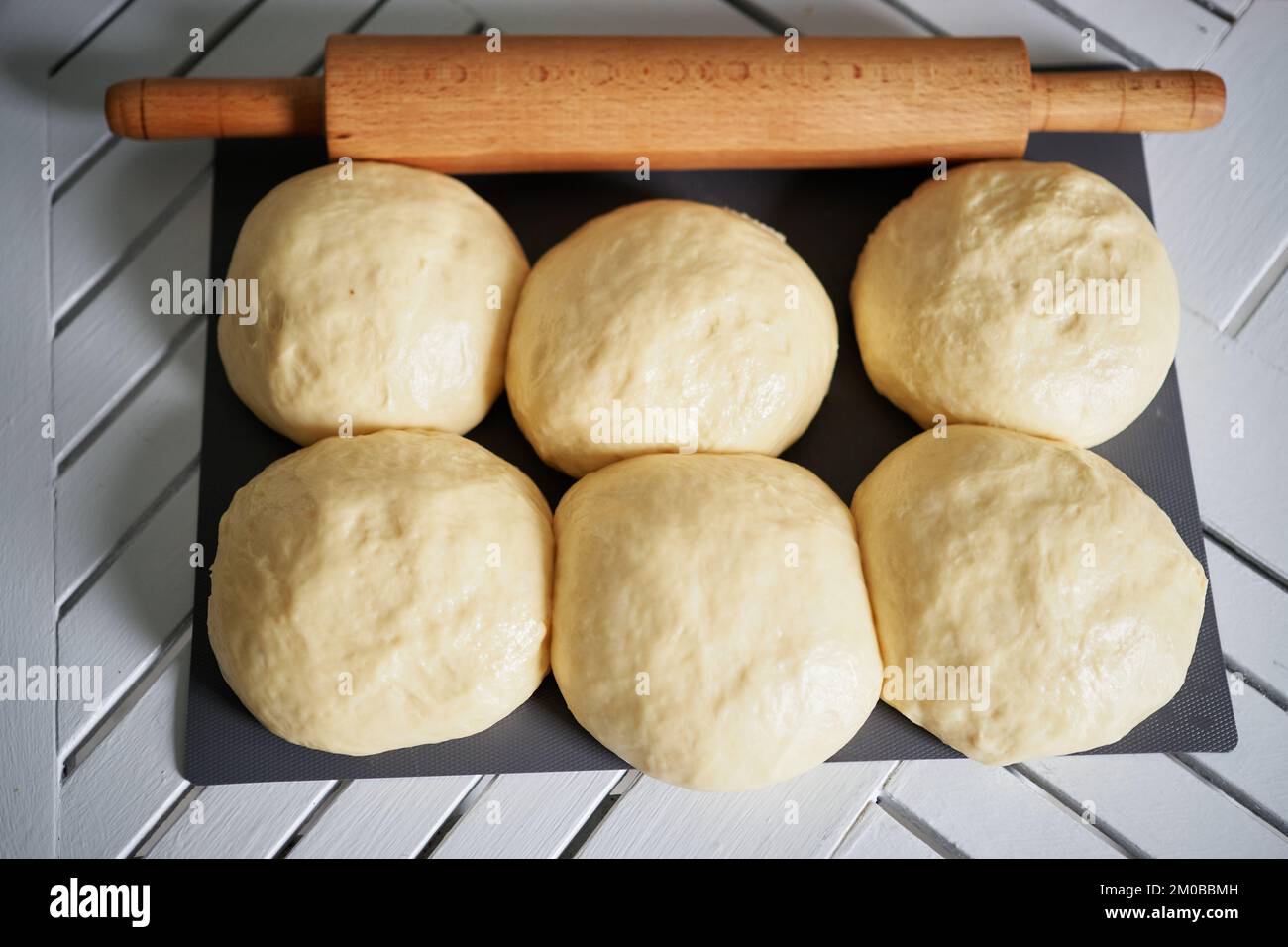 Rollnadel und Teigkugeln auf einem Holzbrett, weicher, selektiver Fokus. Kleine Teigkugeln mit Mehl für Pizza oder Kuchen und Scones. Geringe Schärfentiefe. Hochwertiges Foto Stockfoto