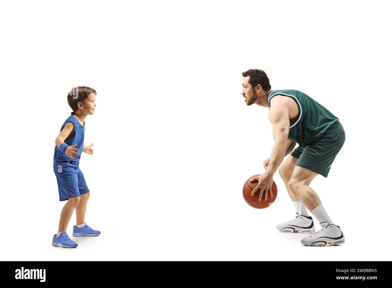 Profilaufnahme über die gesamte Länge eines Erwachsenen, der Basketball spielt, mit einem kleinen Jungen isoliert auf weißem Hintergrund Stockfoto
