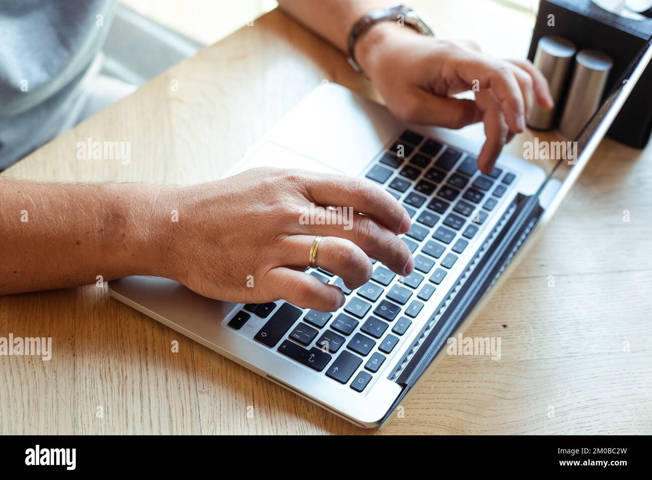 Unbekannte, verkürzte Hände, die an einem Laptop in einem hellen Internetcafe arbeiten. Geschäftsfinanzbranche und IT, Marketing Stockfoto